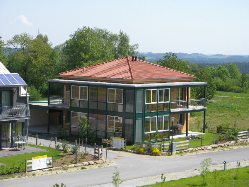 Modernes Holzhaus mit Glasfronten, dunkler Fassade und Walmdach.
