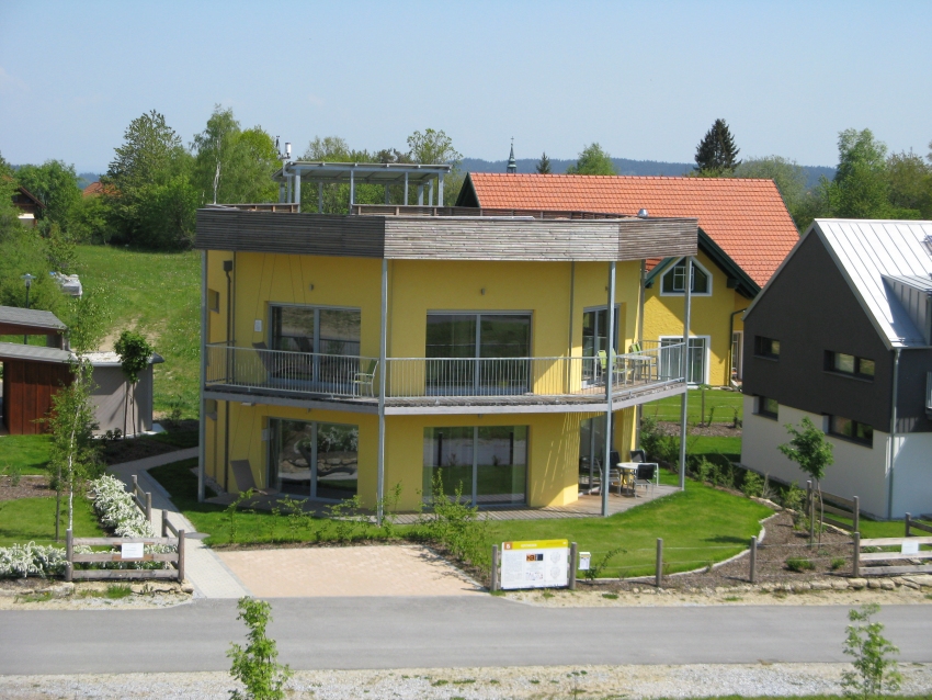 Gelbes, achteckiges Haus mit zwei Etagen und umlaufenden Balkonen.